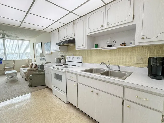 a kitchen with stainless steel appliances granite countertop a sink dishwasher a stove and white cabinets
