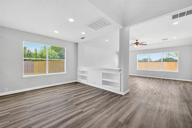 an empty room with wooden floor and windows