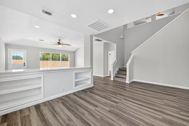 a view of an empty room with wooden floor and a window
