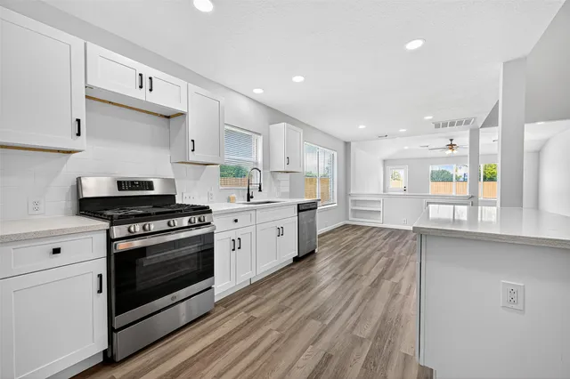 a kitchen with stainless steel appliances white cabinets granite counter tops and a hard wood floors