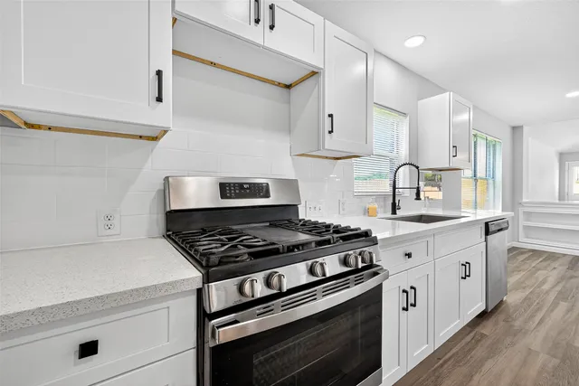 a kitchen with white cabinets a sink and a stove