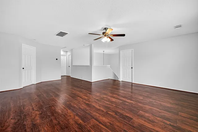 a view of an empty room with a window and wooden floor