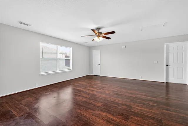 an empty room with wooden floor and ceiling fan