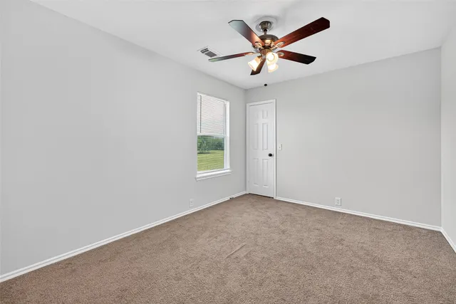 an empty room with ceiling fan and window