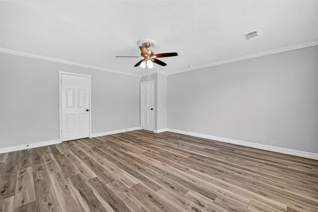 a view of empty room with wooden floor and fan