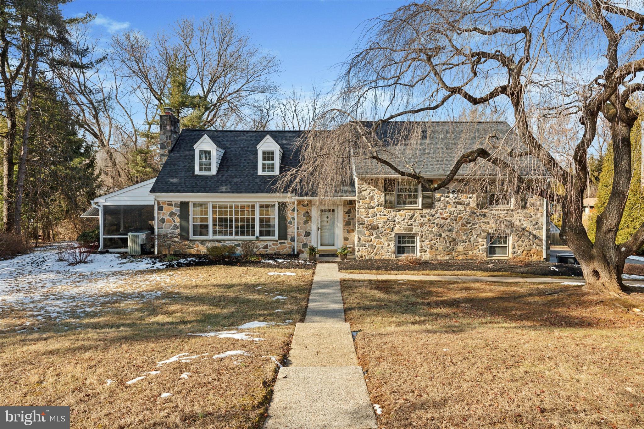 a front view of a building with a garden and trees