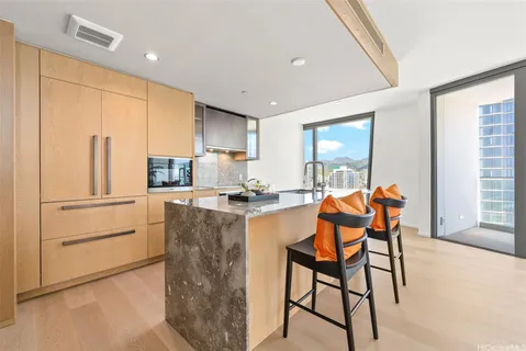 a kitchen with stainless steel appliances granite countertop a stove a refrigerator a microwave a dining table and chairs with wooden floor