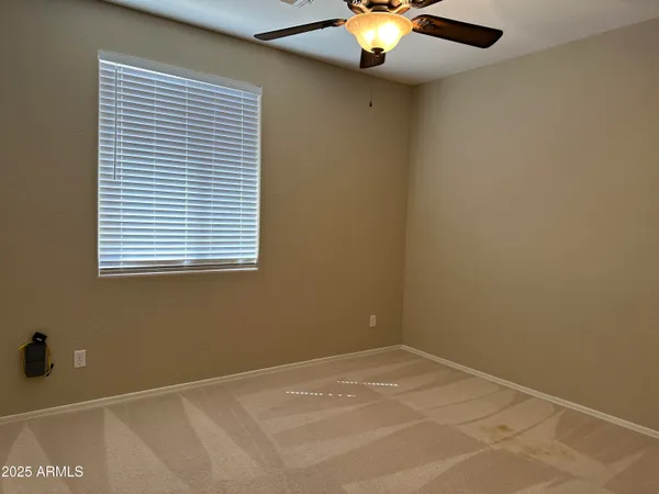 an empty room with a ceiling fan and carpet