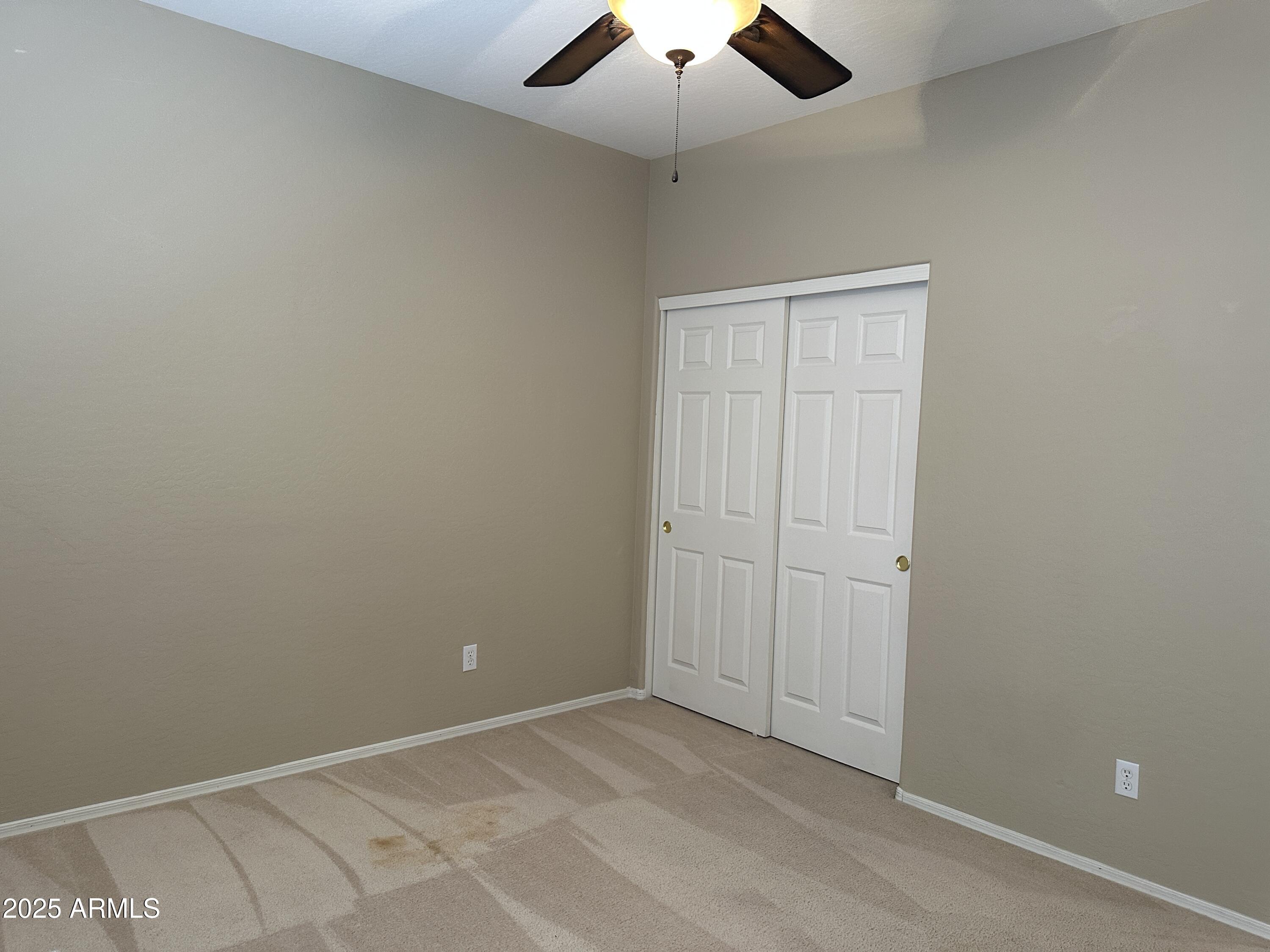 10460 South 182nd Drive Goodyear, AZ 85338 - Photo 15 of 33 an empty room with a ceiling fan and carpet