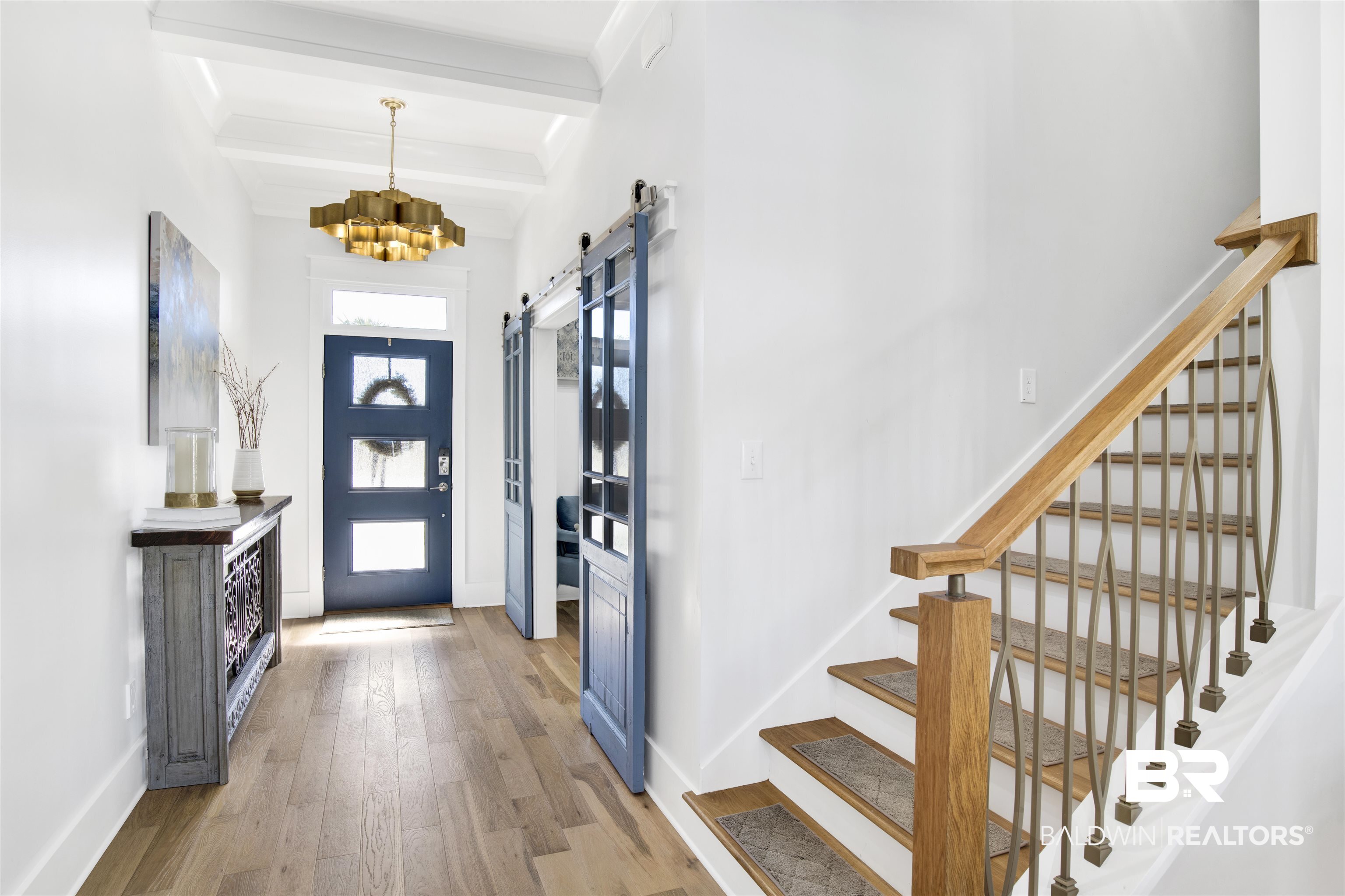 32937 River Road Orange Beach, AL 36561 - Photo 5 of 42 Entrance foyer with beamed ceiling, a barn door, an inviting chandelier, and light hardwood / wood-style flooring
