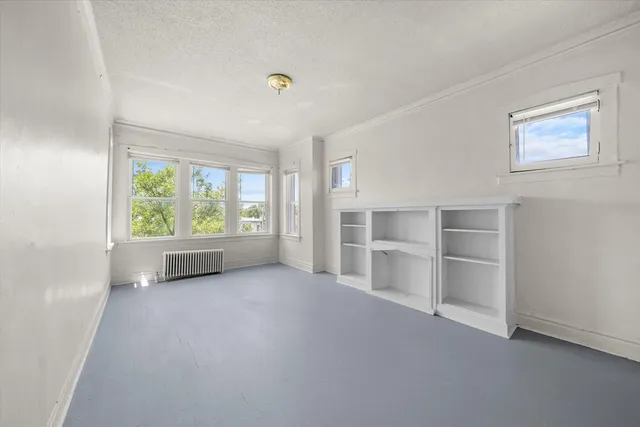 an empty room with a window and cabinet