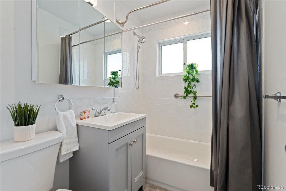 2597 South Perry Street Denver, CO 80219 - Photo 12 of 33 a bathroom with a sink a mirror a potted plant and a bathtub