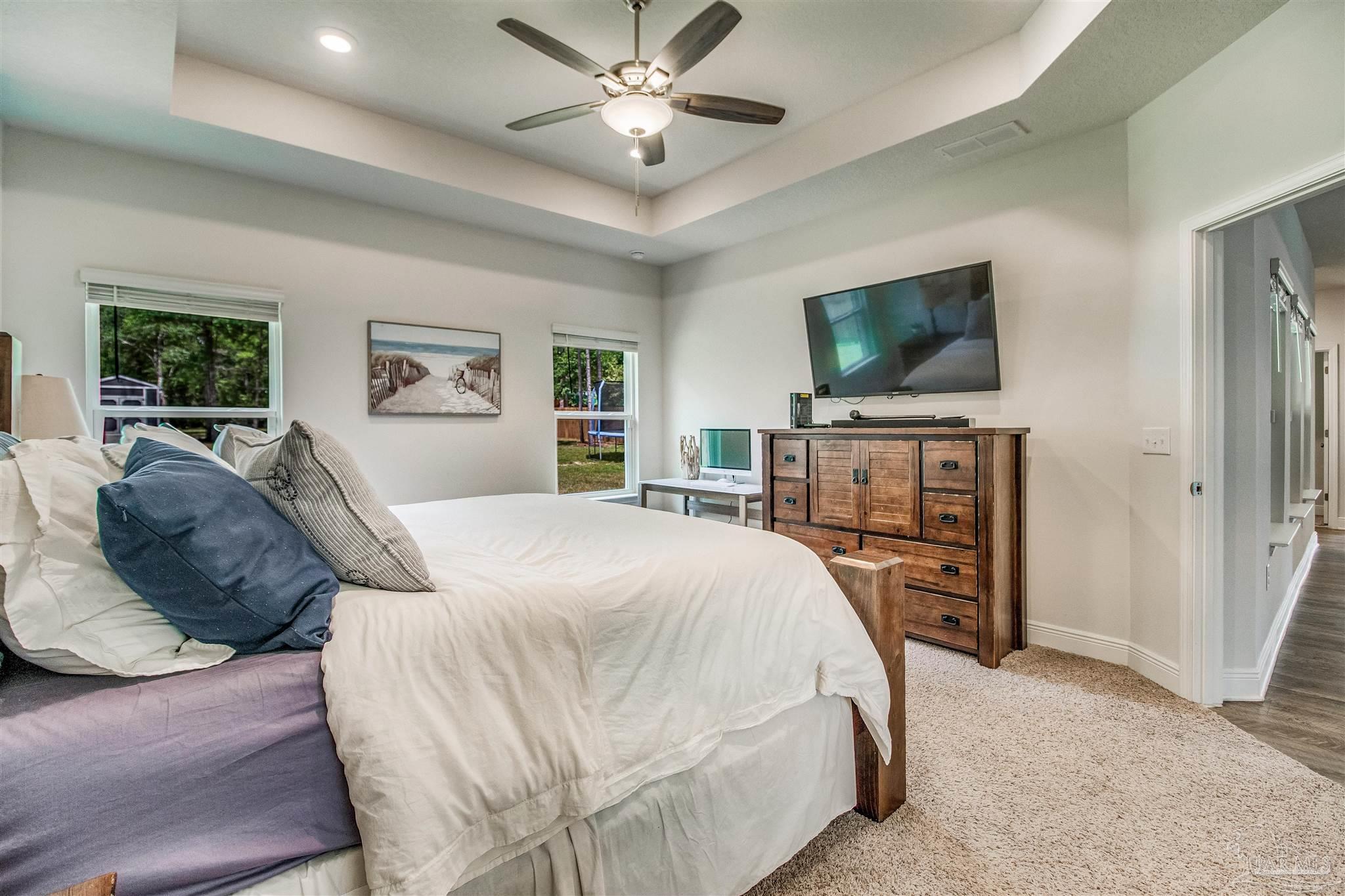 8024 Silver Maple Drive Milton, FL 32583 - Photo 14 of 43 a bedroom with a bed flat screen tv and a couch