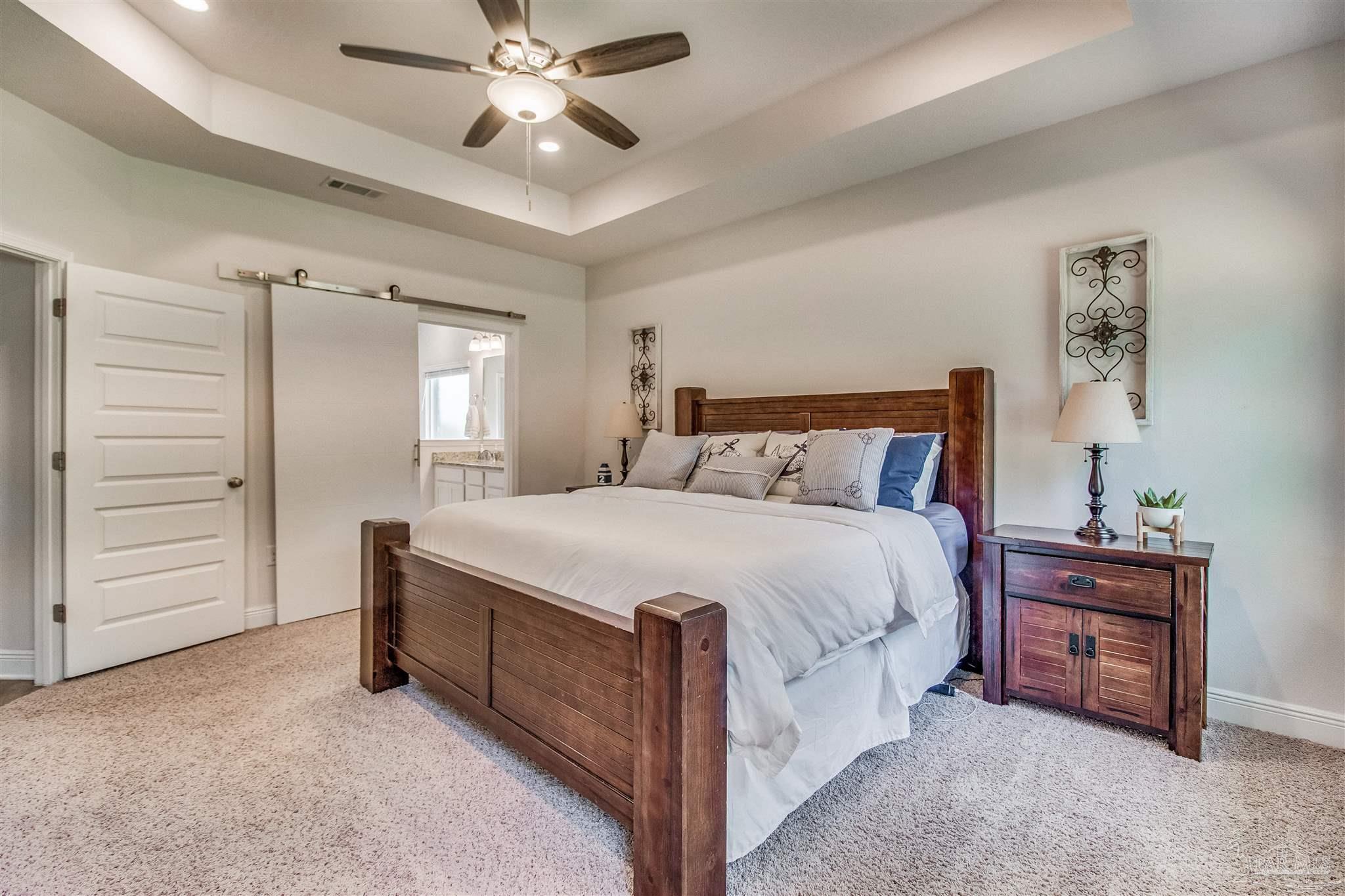 8024 Silver Maple Drive Milton, FL 32583 - Photo 16 of 43 a spacious bedroom with a bed and a ceiling fan