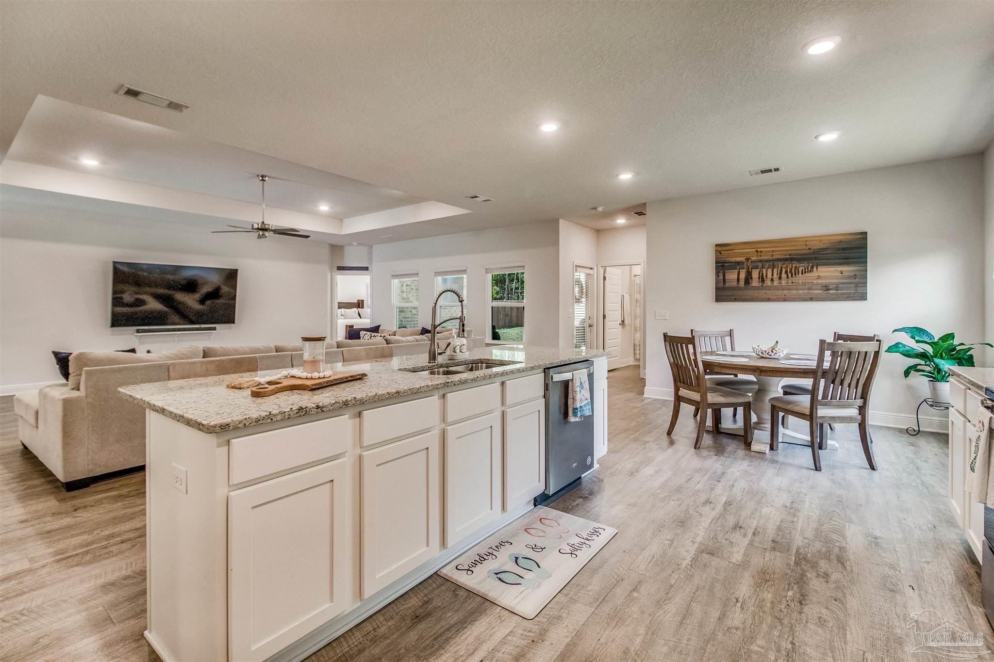 8024 Silver Maple Drive Milton, FL 32583 - Photo 5 of 43 a kitchen with stainless steel appliances kitchen island granite countertop a sink a stove a dining table and chairs