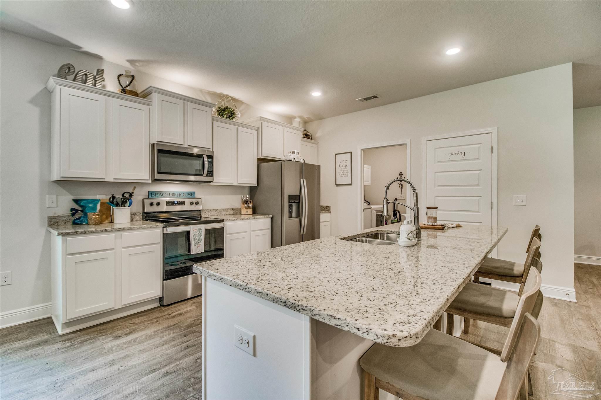8024 Silver Maple Drive Milton, FL 32583 - Photo 6 of 43 a kitchen with kitchen island a counter top space appliances and cabinets
