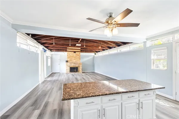 a room with kitchen island a ceiling fan and wooden floor