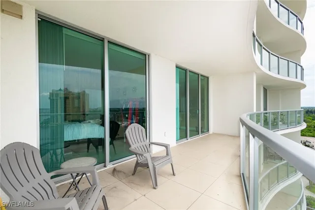 a balcony with chairs and a potted plant