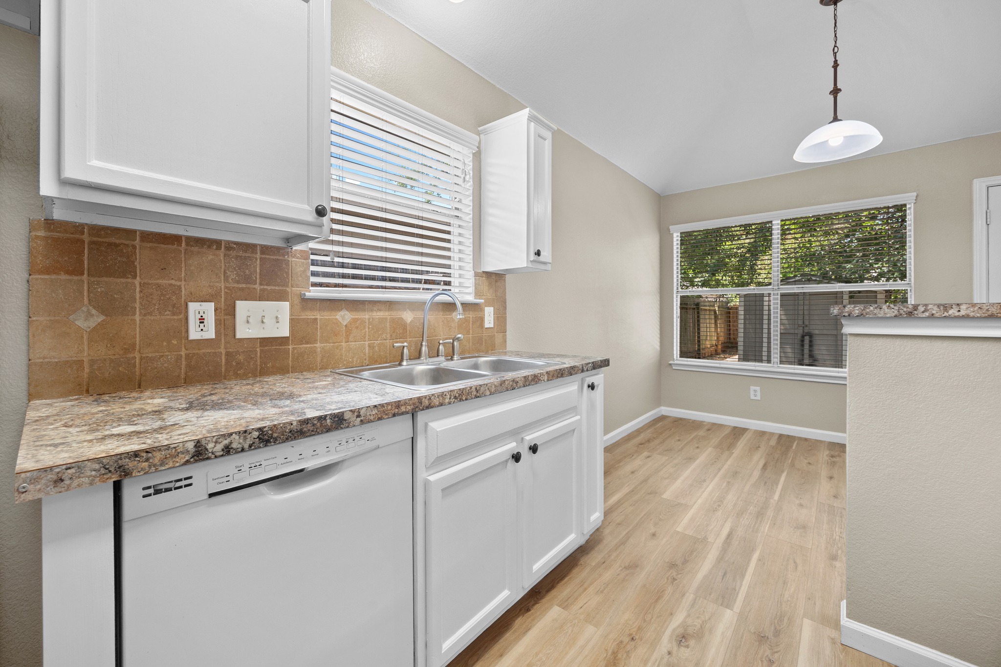 1806 Rusty Nail Loop Round Rock, TX 78681 - Photo 14 of 28 A well-lit kitchen with light wood flooring and white cabinetry.