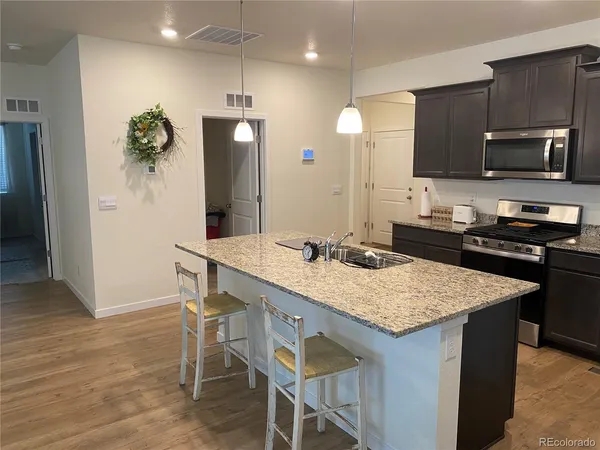 a kitchen with stainless steel appliances granite countertop wooden floor and refrigerator