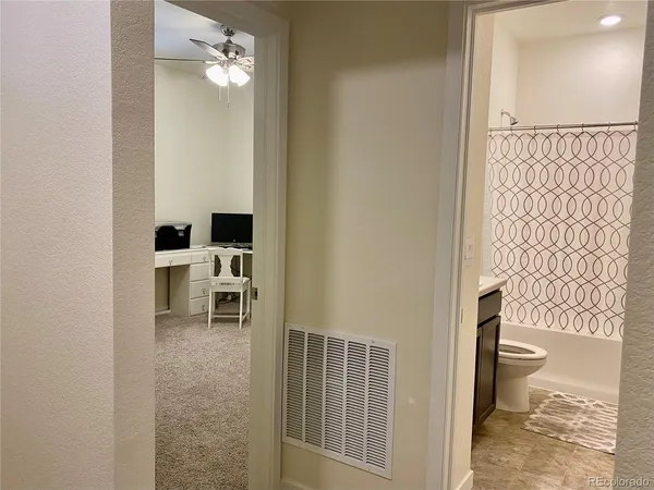 a view of a hallway with wooden floor and a bathroom