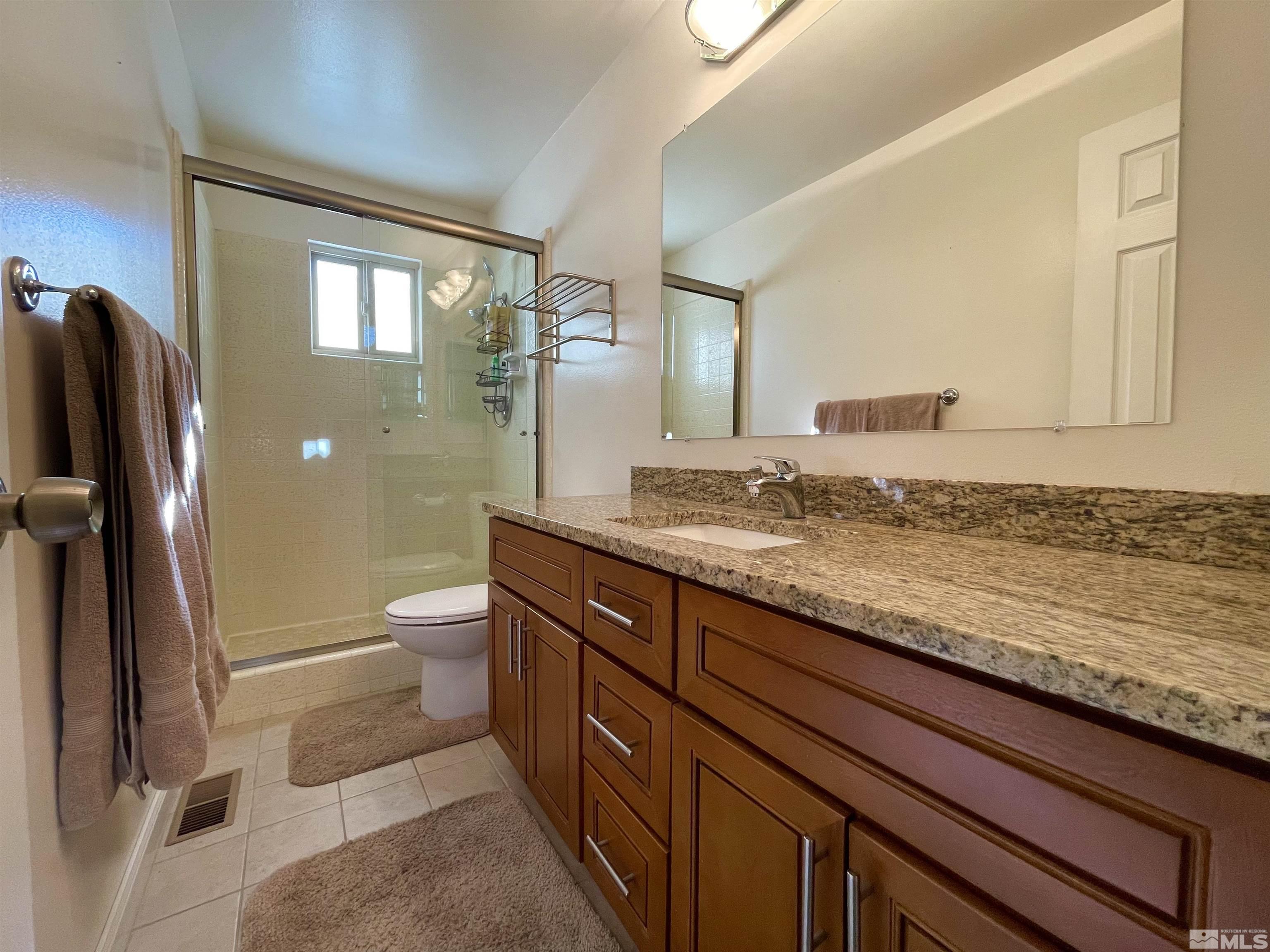 126 Spooner Lane, Unit B Stateline, NV 89449 - Photo 15 of 37 a bathroom with a granite countertop sink a toilet and a mirror