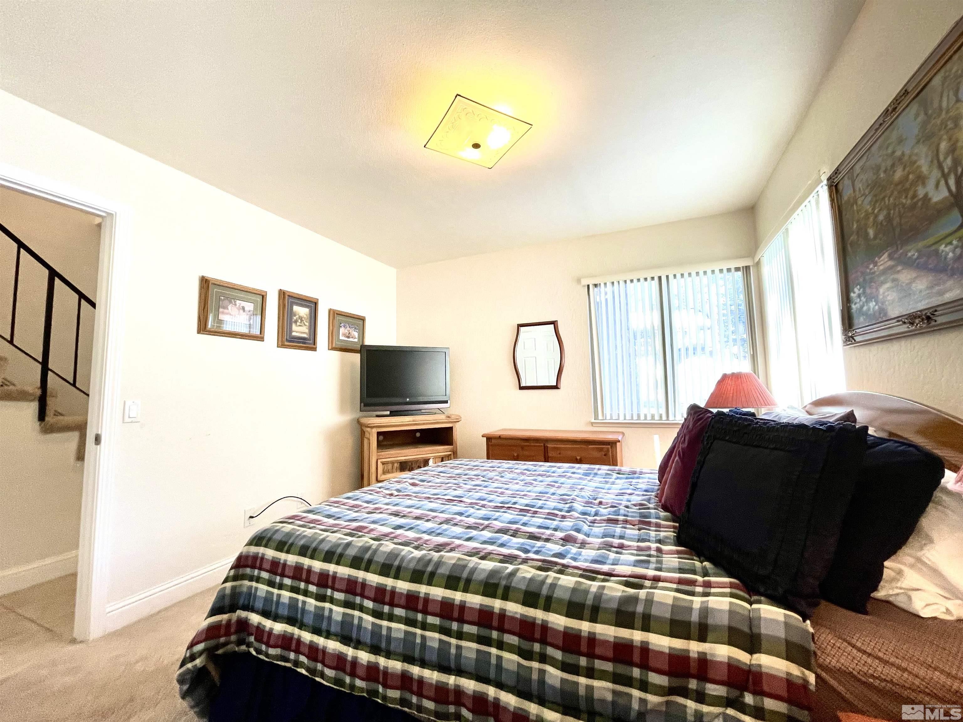 126 Spooner Lane, Unit B Stateline, NV 89449 - Photo 17 of 37 a bedroom with a large bed and a flat tv screen on dresser