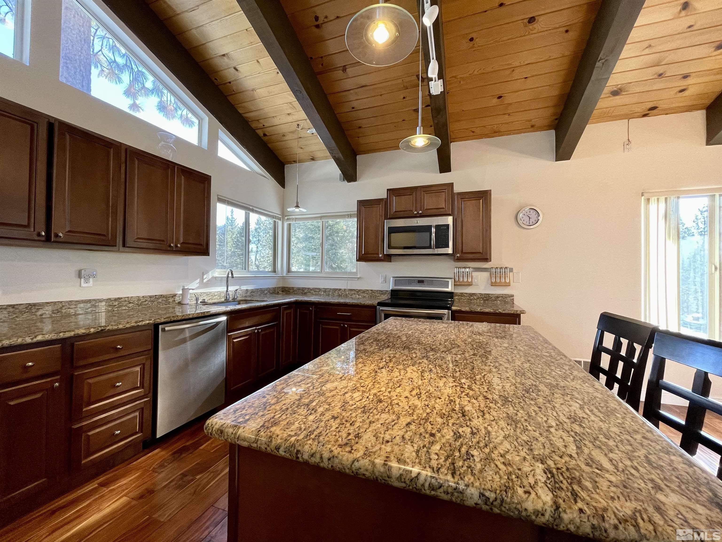 126 Spooner Lane, Unit B Stateline, NV 89449 - Photo 6 of 37 a large kitchen with a stove a sink dishwasher a dining table and chairs with wooden floor