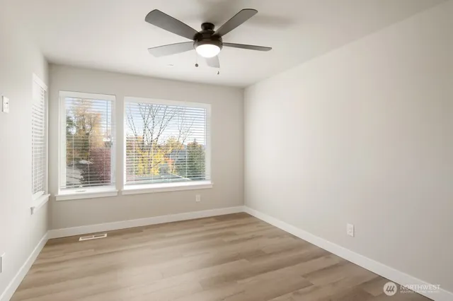 an empty room with wooden floor and windows