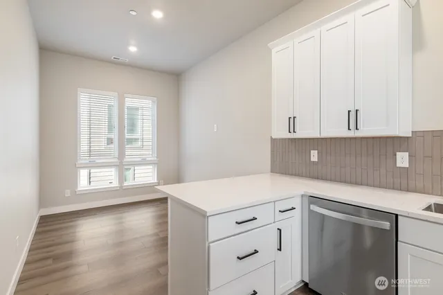 a kitchen with white cabinets and a window