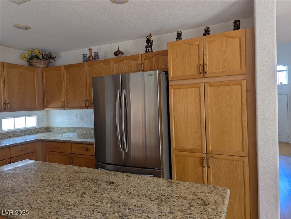 4777 Crakow Court Las Vegas, NV 89147 - Photo 45 of 49 Kitchen featuring freestanding refrigerator, light stone countertops, plenty of natural light, and wood finished floors