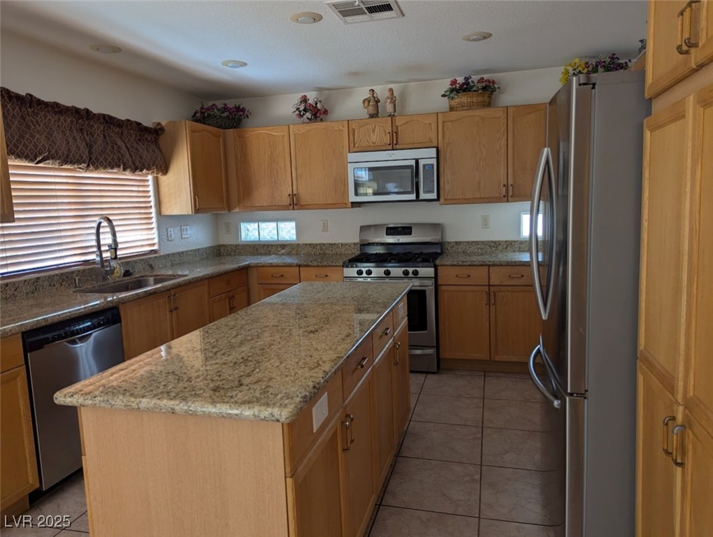 4777 Crakow Court Las Vegas, NV 89147 - Photo 46 of 49 Kitchen featuring stainless steel appliances, light tile patterned flooring, light stone counters, and a kitchen island