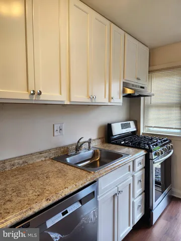 a kitchen with granite countertop a stove sink and cabinets