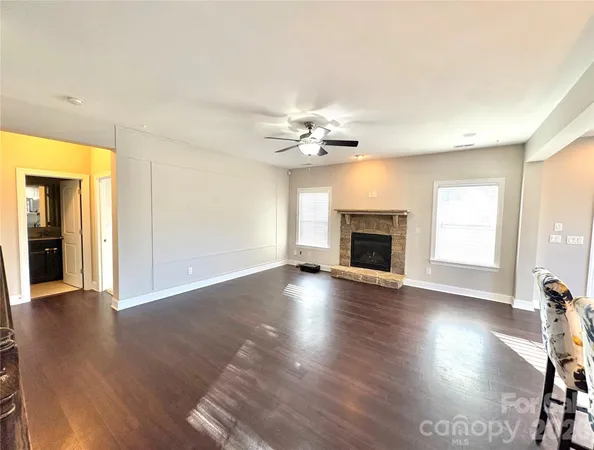 an empty room with wooden floor fireplace and windows