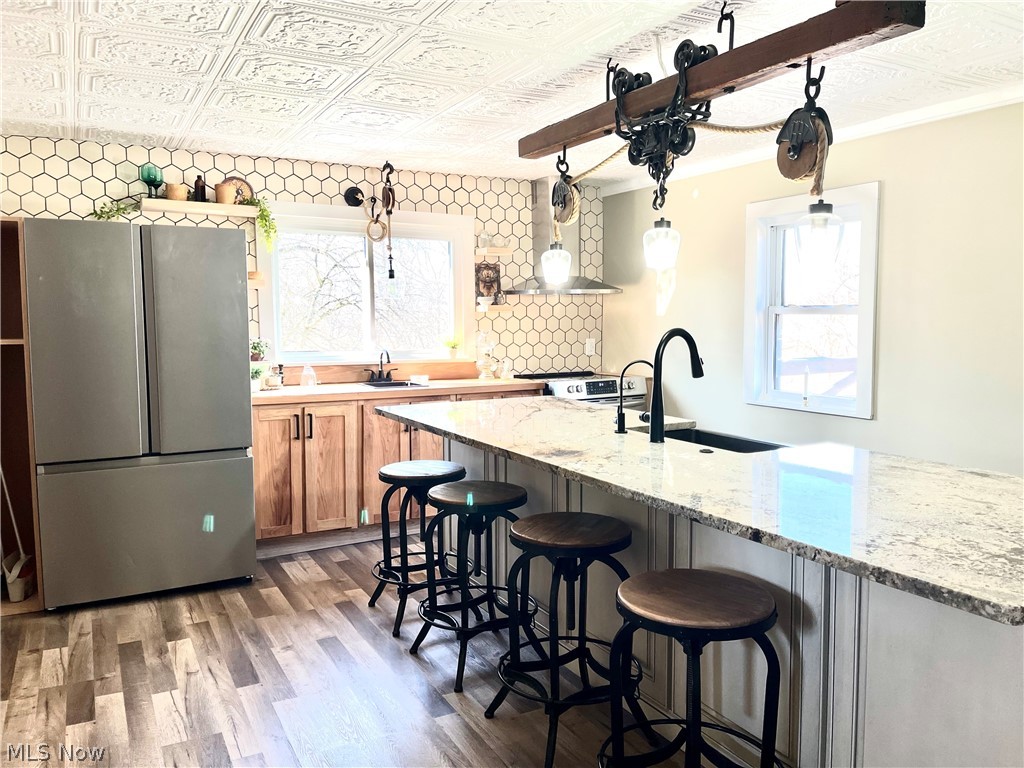 12972 Gilmore Road Southeast Port Washington, OH 43837 - Photo 10 of 50 Kitchen with an ornate ceiling, stainless steel appliances, light wood finished floors, a kitchen bar, and healthy amount of natural light