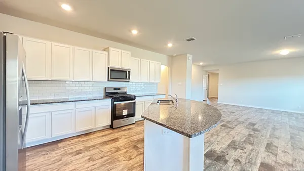 a kitchen with granite countertop a stove top oven a sink and a refrigerator