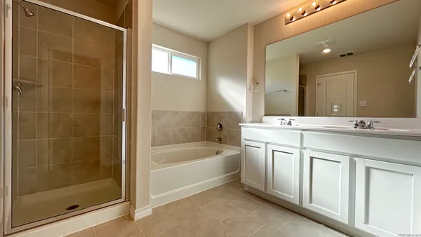 a bathroom with a bathtub sink vanity and mirror