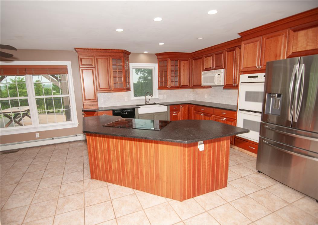 2202 High Meadow Road Coopersburg, PA 18036 - Photo 8 of 41 A spacious kitchen features warm wood cabinetry, a central island, and tiled flooring.