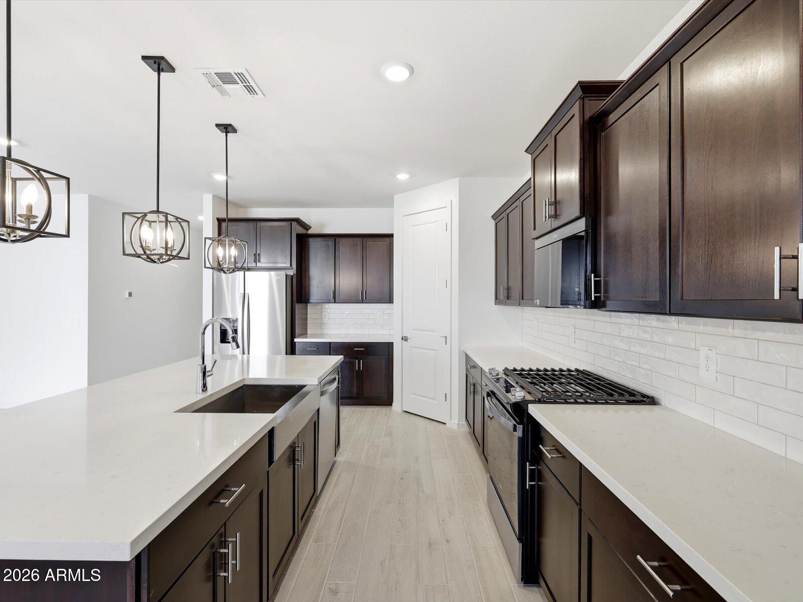 2392 Grenache Road San Tan Valley, AZ 85143 - Photo 21 of 67 a kitchen with stainless steel appliances granite countertop a sink a stove and a refrigerator
