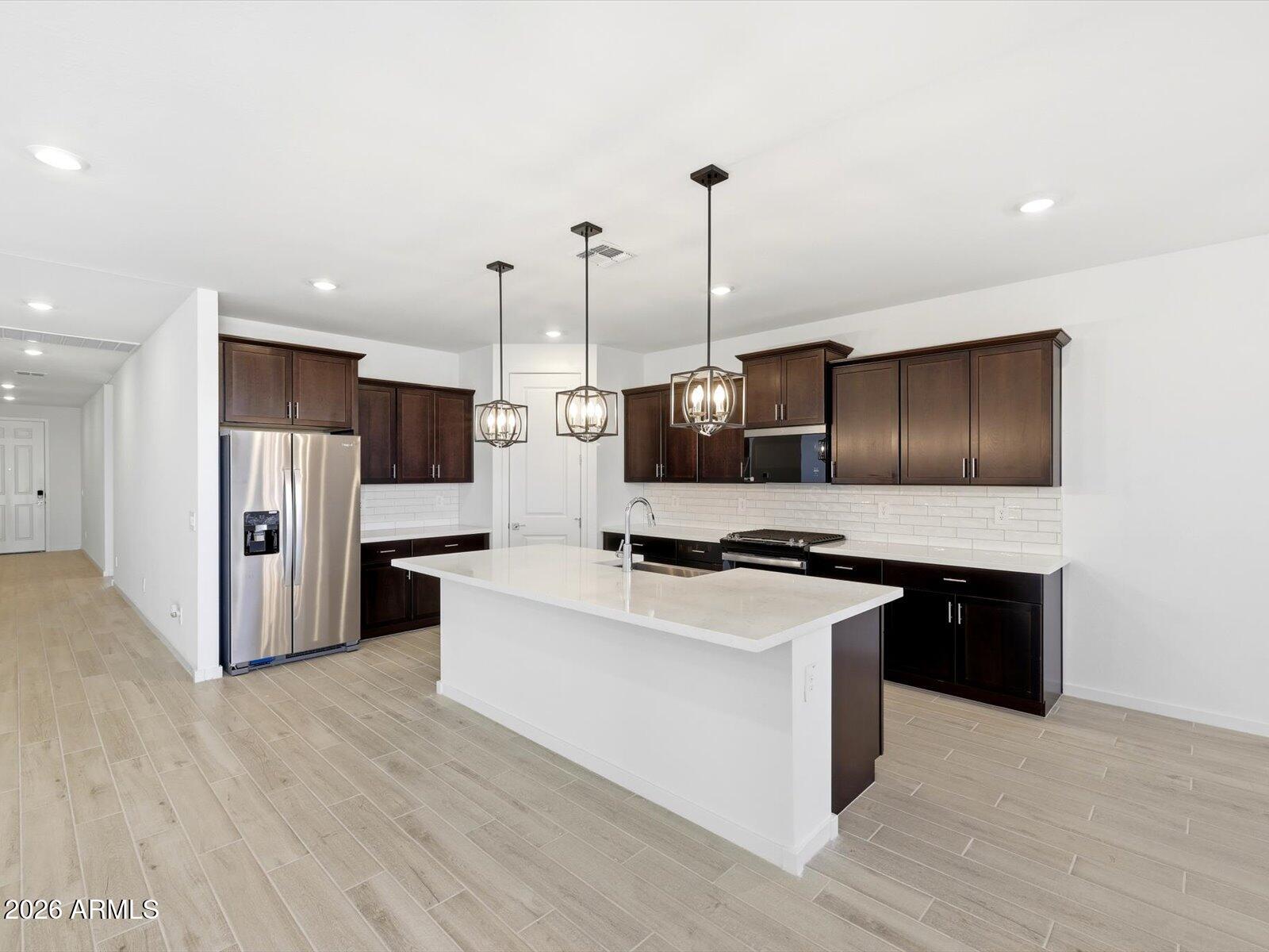2392 Grenache Road San Tan Valley, AZ 85143 - Photo 25 of 67 a kitchen with stainless steel appliances a stove top oven a refrigerator a sink and a wooden floor