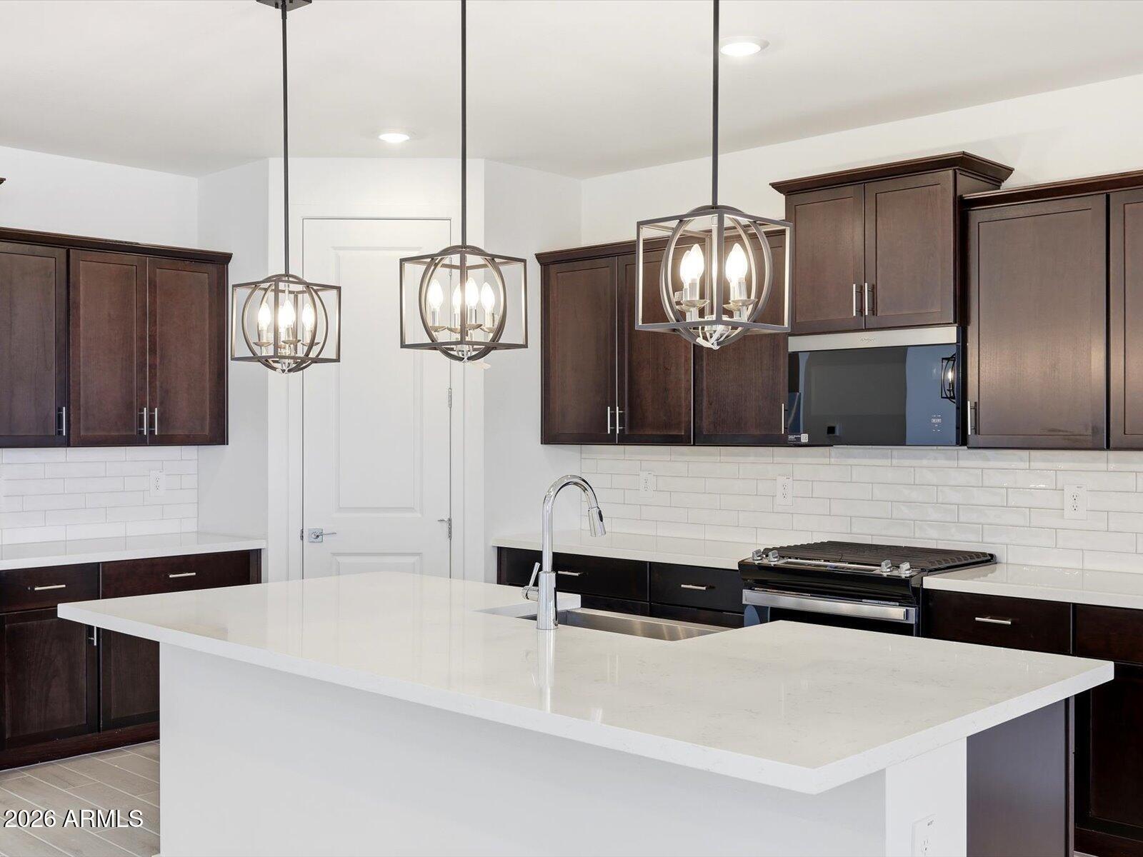 2392 Grenache Road San Tan Valley, AZ 85143 - Photo 26 of 67 a kitchen with stainless steel appliances kitchen island a refrigerator and a chandelier