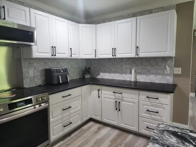 a kitchen with granite countertop white cabinets and stainless steel appliances