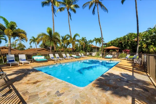 a view of a swimming pool with a lawn chairs under an umbrella