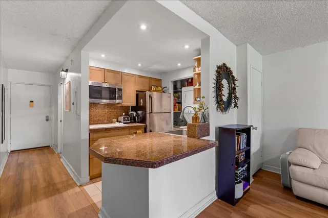 a view of kitchen with stainless steel appliances granite countertop sink stove refrigerator and wooden floor