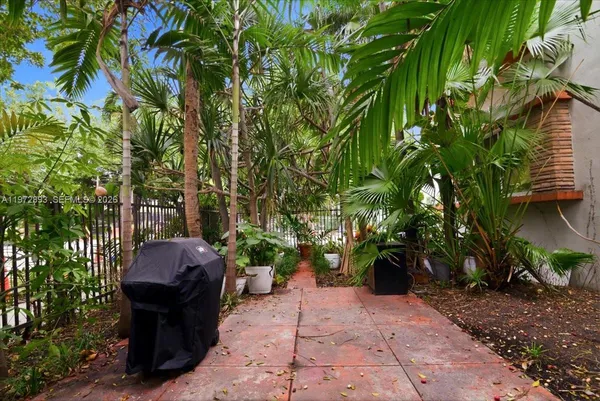 a view of a path along with potted plants and large trees