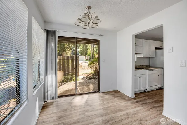 a view of a hallway with wooden floor and a kitchen