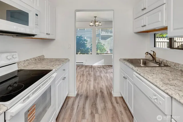 a kitchen with granite countertop a sink dishwasher stove and cabinets with wooden floor