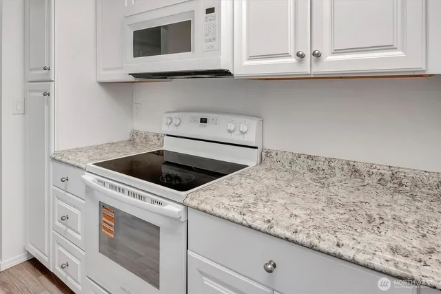 a kitchen with granite countertop white cabinets and white appliances