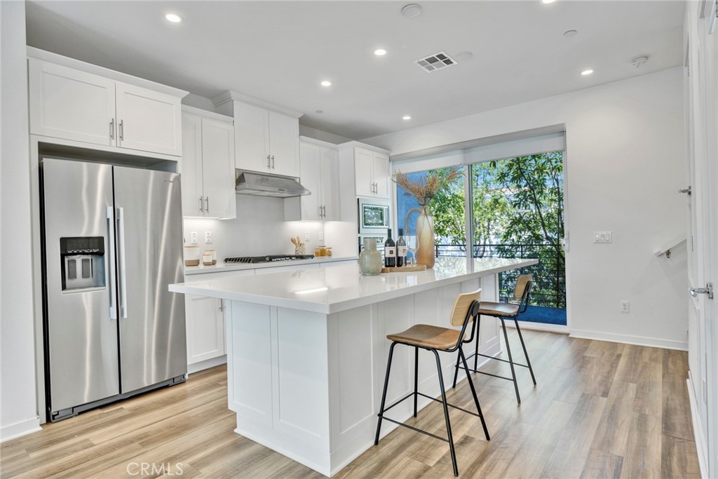 105 Schick Irvine, CA 92614 - Photo 4 of 39 a kitchen with stainless steel appliances a dining table chairs refrigerator and wooden floor