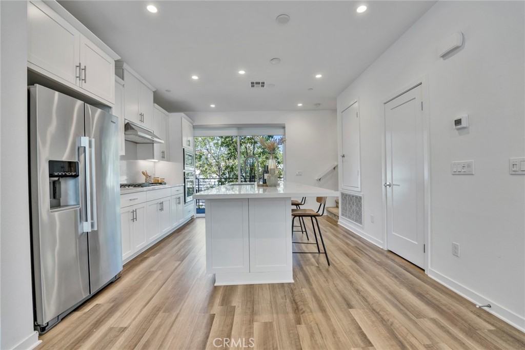 105 Schick Irvine, CA 92614 - Photo 5 of 39 a kitchen with stainless steel appliances a refrigerator a sink dishwasher a stove and white cabinets with wooden floor